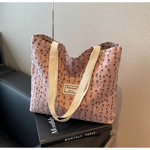 Gros plan sur un sac cabas en velours côtelé rose avec motifs floraux et anses tissées