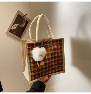 Detailed texture of red and yellow plaid linen tote bag with soft plush bird charm