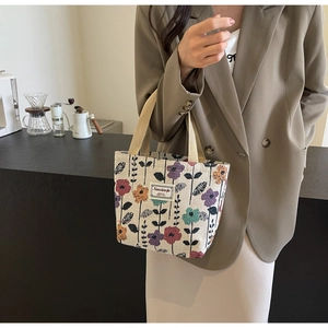 Detail of vintage floral print canvas tote bag held by model in a cozy coffee shop