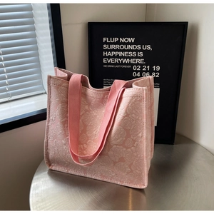 Détail du tissu jacquard floral rose et des poignées tissées robustes du sac