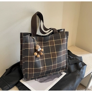 Dettaglio della borsa tote vintage in tela scozzese con manici e ciondolo a scimmietta