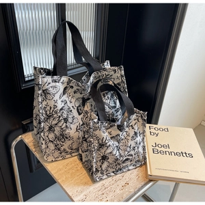 Detail view of two floral canvas tote bags with vintage prints on a marble surface