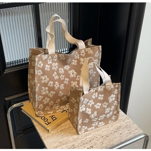 Close-up of khaki canvas tote bags with white floral embroidery and sturdy straps