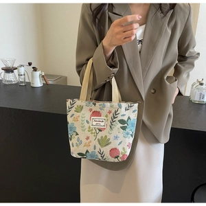 Detail of floral jacquard canvas tote bag with woven brand label and beige straps