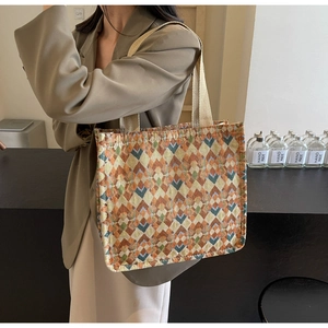 Detail of bohemian woven tote bag with orange geometric patterns and fabric handles