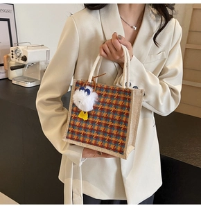 Detail of colorful houndstooth woven tote bag with a white rope handle and plush duck charm
