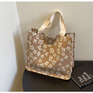 Close-up of khaki canvas tote bag with white jacquard flower patterns on a table