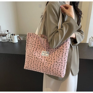 Détail du cabas en velours côtelé rose avec motif floral et sangles blanc cassé
