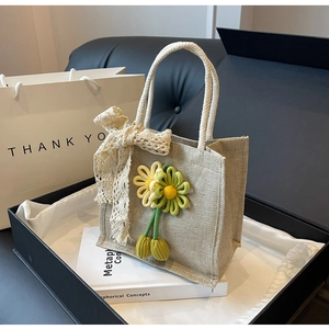 Détail de la texture d'un sac en lin avec tournesol tricoté et nœud en dentelle