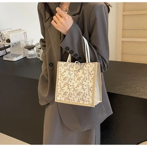 Dettaglio della borsa tote floreale con tessuto crema, motivi marroni e manici in corda