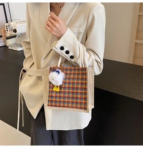 Linen tote bag detail with colorful plaid pattern and white plush chick pendant accessory