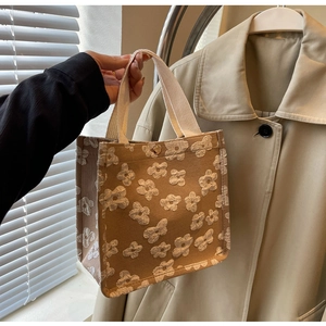 Detail of canvas tote bag with 3D white floral patterns and golden metal snap button