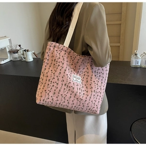 Détail de la texture en velours côtelé rose à fleurs avec étiquette tissée sur le sac