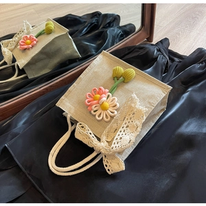 Détail du sac en toile avec fleurs au crochet, nœud en dentelle et poignée en corde de coton