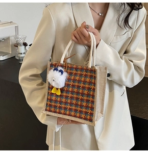 Macro detail of colorful plaid linen tote bag with natural cotton rope handles and plush charm