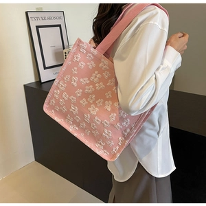 Detail view of pink jacquard tote bag with white floral pattern and wide shoulder strap