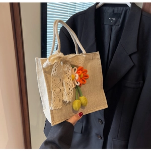 Détail d'un sac en jute avec nœud en dentelle et fleurs au crochet sur la poignée