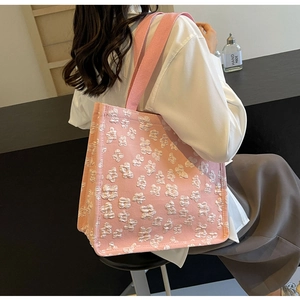Detail of pink canvas tote bag featuring 3D white flower embroidery and strap handles