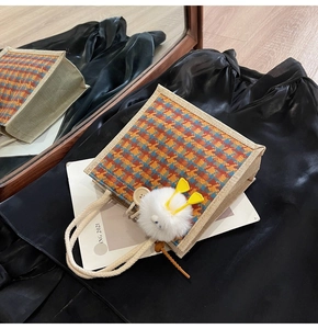 Close-up of linen houndstooth bento bag with rope handle and plush pendant