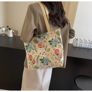 Detail of vintage floral jacquard tote bag with beige cotton strap worn by a model