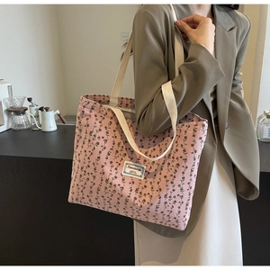 Sac fourre-tout en velours côtelé rose à fleurs porté par un mannequin élégant