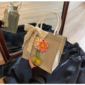 Détail du sac à main en lin beige orné de fleurs tricotées en 3D et d'un nœud en dentelle