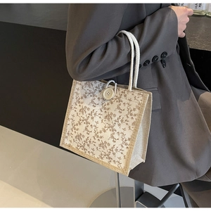 Dettaglio della borsa a fiori con chiusura a bottone grande e manico in corda intrecciata