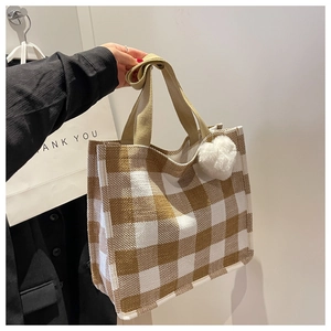 Détail du sac cabas en toile à carreaux avec breloque cœur et anses en tissu marron