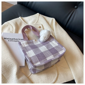 Détail du sac cabas tissé à carreaux violets avec pompon en peluche sur veste en tweed