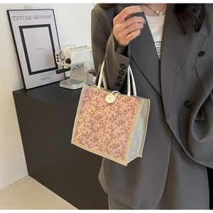 Dettaglio borsa in tela a fiori rosa con manici in corda bianca e chiusura con bottone