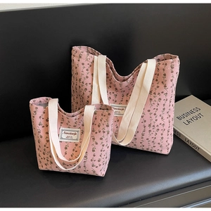 Détail d'un ensemble de sacs cabas en velours côtelé rose à fleurs avec étiquette