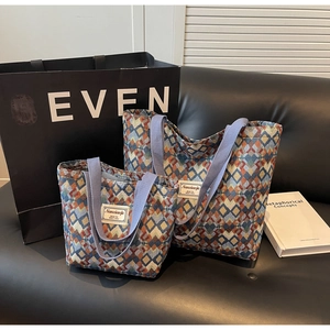 Close-up of geometric woven tote bags in two sizes with purple handles on a leather sofa