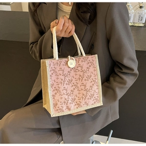 Dettaglio del motivo floreale e cuciture in canapa rustica sulla mini borsa shopper