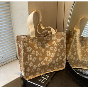 Detail of 3D floral embroidery on brown canvas tote bag with textured cream flowers