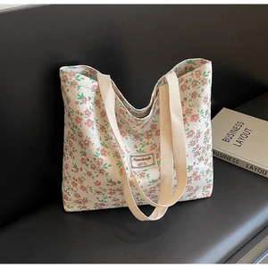Détail du sac cabas floral avec texture velours et poignées en tissu sur un banc