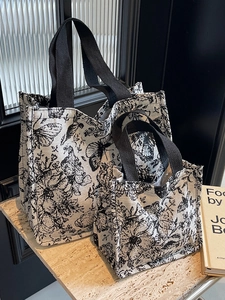 Set of two vintage floral canvas tote bags with black straps on a marble surface