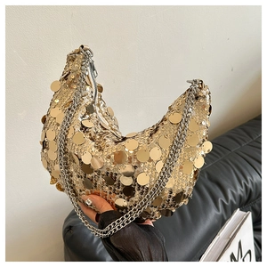 Détail du sac demi-lune à paillettes dorées avec bandoulière chaîne sur fond de cuir noir
