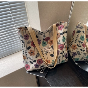 Detail of vintage floral canvas tote bag showing wide woven handle and retro flower pattern