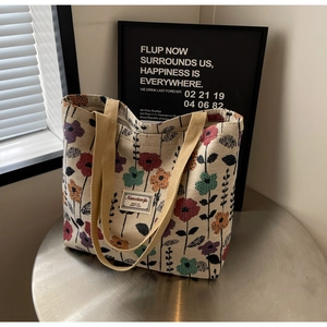 Detail of floral tapestry tote bag on a metal table featuring high-texture fabric weave