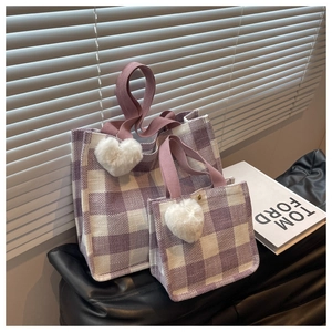 Détail d'un ensemble de sacs cabas en toile à carreaux violet et blanc avec charme de cœur