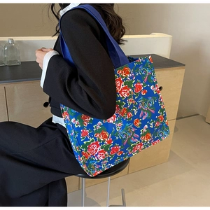 Detail view of the floral canvas tote bag showing the vibrant rose pattern and blue strap