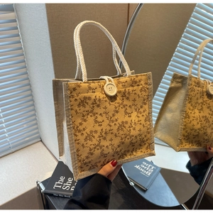 Dettaglio della borsa floreale con chiusura a bottone bianco e manico in corda intrecciata