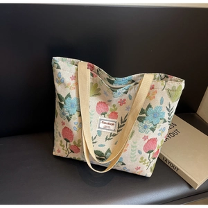 Detail of floral woven tote bag with sturdy beige handles and secure zipper closure