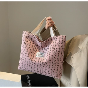 Gros plan du sac fourre-tout en velours côtelé rose avec motif floral et étiquette tissée