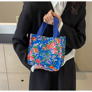 Detail of blue canvas tote bag with vintage rose pattern and gold metal snap button