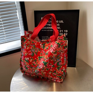 Close-up of a floral canvas tote bag featuring vibrant folk patterns and red handles