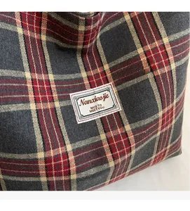 Detail of plaid canvas tote bag showing tight fabric texture and stylish brand label