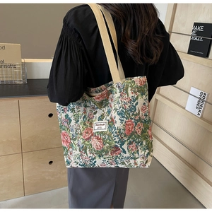 Detailed close-up of a floral tapestry tote bag with cotton straps and woven label