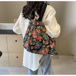 Detail of large tote bag with red and green floral print on black canvas material