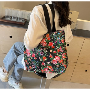 Close-up of vintage floral canvas tote bag with thick black straps and red rose pattern